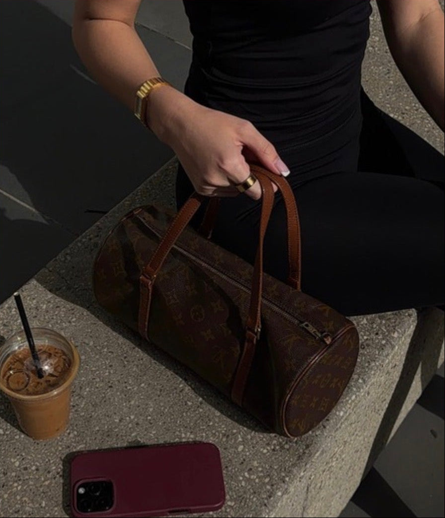 Person holding a brown leather duffel bag with text on a red background